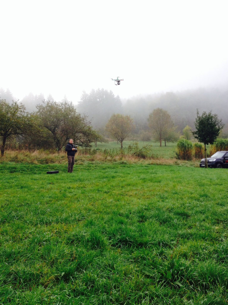 Herbstlicher Tag im Freien, große Wiese. Ralf steuert die Phantom-Drohne in der Luft