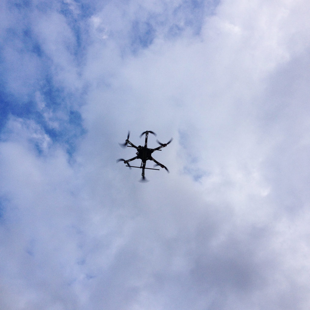 Selbstgebauter Hexacopter in der Luft vor wolkigem Himmel.
